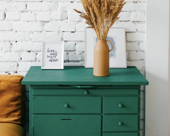 Green chest of drawers with vase and pictures